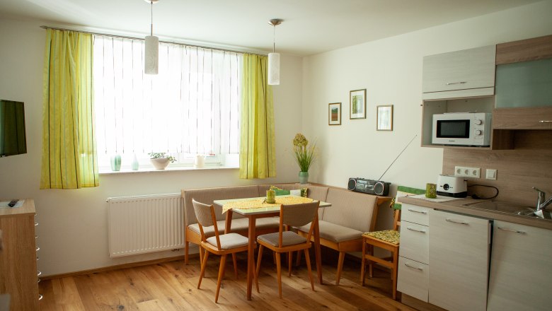 Eat-in kitchen, © Michael Sokolar Cozy eat-in kitchen with dining table, corner bench, kitchenette and green curtains.