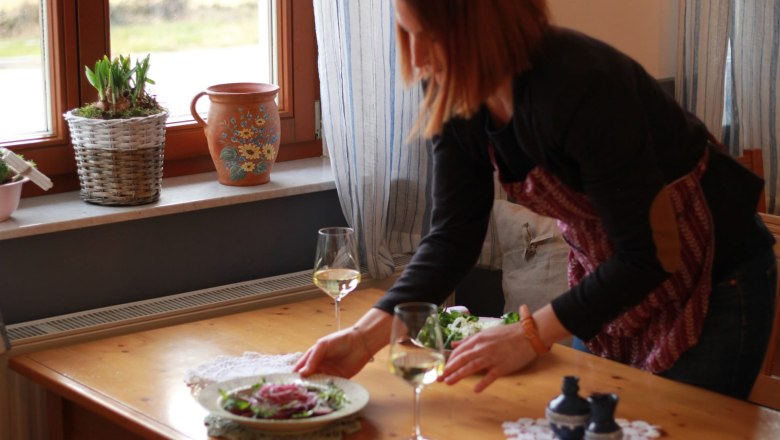 Buschenschank (typical tavern) Demmer, © Thomas Norek A woman sets a table with salad and white wine.