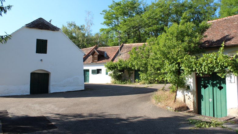 Untermarkersdorf wine cellar lane, © Weinviertel Tourismus Traditional wine cellars in a rural setting with trees and blue skies.