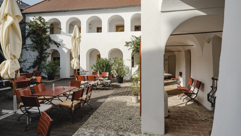 Eisenhuthaus courtyard, © Michael Reidinger Inner courtyard with white arcades, wooden furniture and parasols.