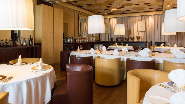Dining room, © Mörwald Elegant dining room with round tables, white tablecloths and brown and beige armchairs.