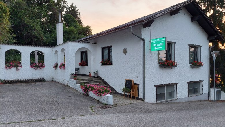 TDR-Welserhof-outside, © Nora Bartfai Exterior view of a white building with flowers and a sign "Pension Welserhof Eingang".