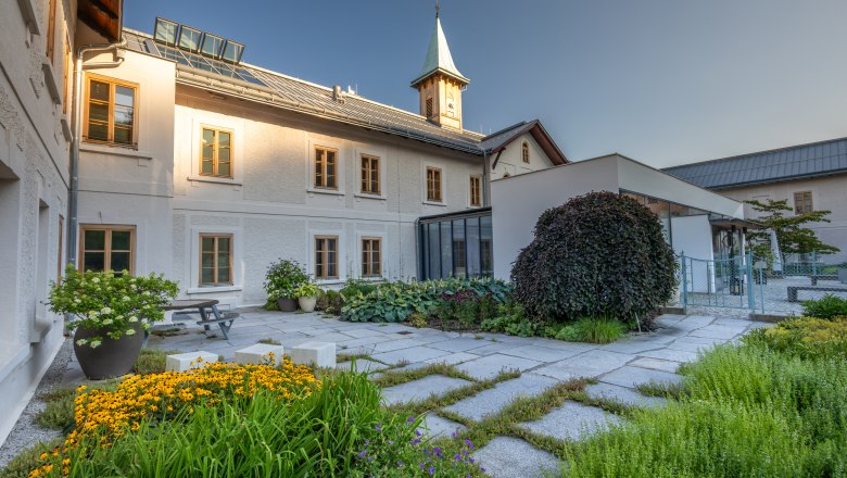 Refugium Hochstrass, © Niederösterreich Werbung / Maximilian Pawlikowsky Inner courtyard of a historic building with garden and tower.