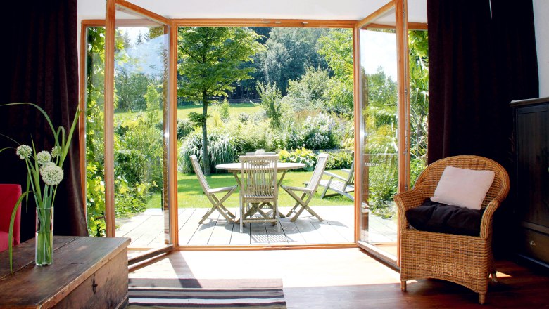 Vacation home Unternberg - Terrace, © Fam. Gruber-List View from a living room onto a terrace with garden furniture and green garden.