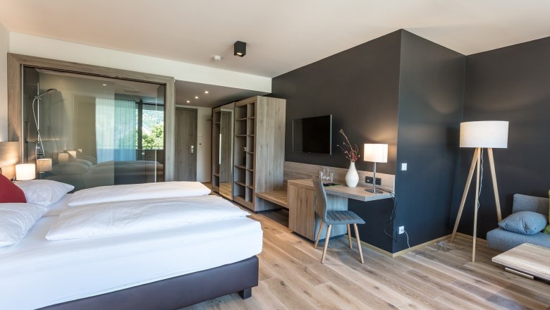 Suite example wine lodge, © KASTNER NEW MEDIA - kastner.tv Modern hotel room with double bed, desk, TV and glass shower.