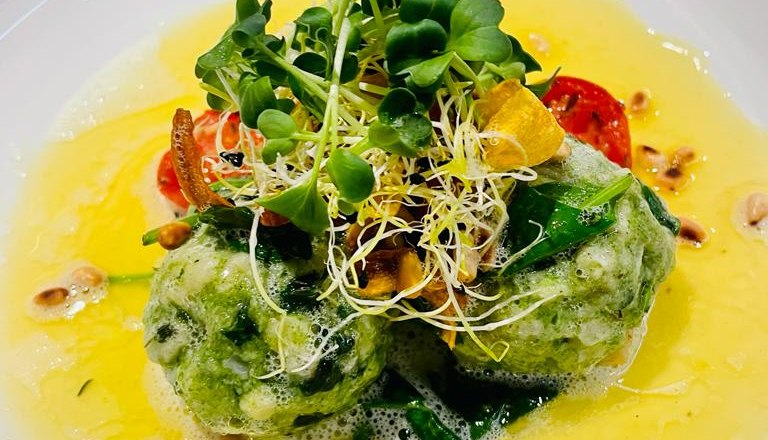 The GrimmenStein fine dining, © Das GrimmenStein White plate with green dumplings, served with sprouts and pine nuts, in a yellow sauce.