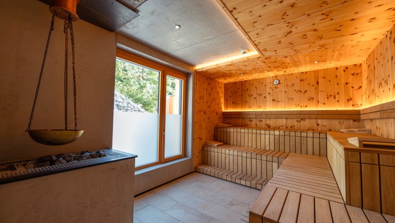 Wine Hotel Nigl, © Niederösterreich Werbung / Maximilian Pawlikowsky Interior view of a modern sauna with wooden walls and benches, a window and a sauna heater.