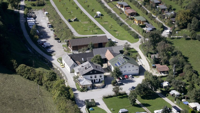 Overview, © L.G Aerial view of a campsite with caravans and buildings in a green landscape.
