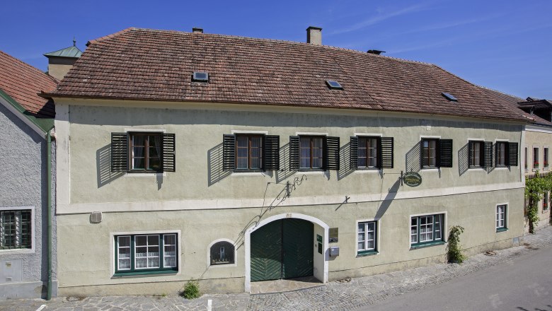 Dinstlhof exterior view, © Monika Loeff Exterior view of a traditional building with green gate and shutters.