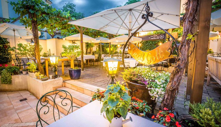 Guest garden, © flotographix Guest garden in the evening with lighting and plenty of seating, plants and umbrellas.