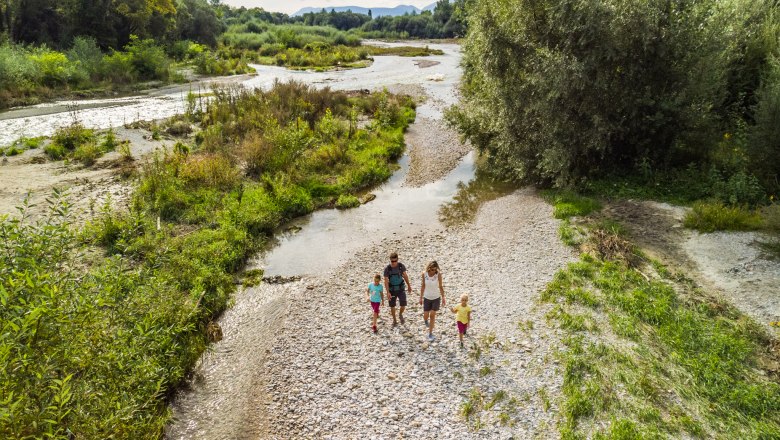 In the Leitha-Au, © Wiener Alpen, Martin Fülöp A family walks through a green river landscape with pebbles and trees. Aerial view