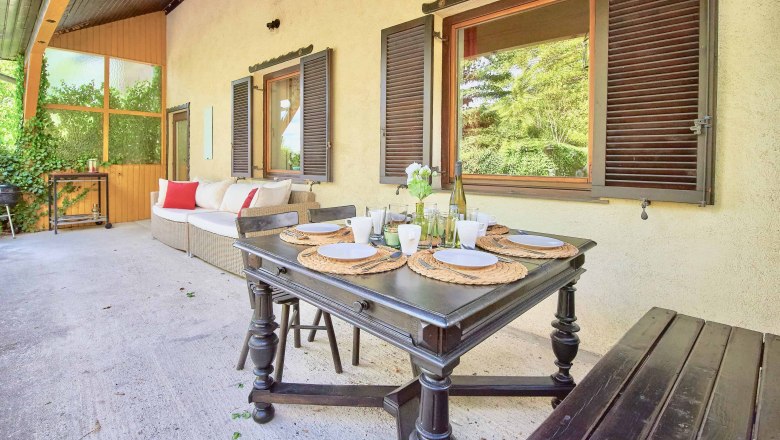 Top 1 - Terrace, © VP FeWo OG Terrace with dining table, chairs and sofa, surrounded by plants.