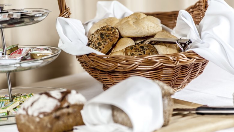 Breakfast, © Imre Antal A breakfast table with a basket full of bread rolls, a bread cutting board and a tray of jams.
