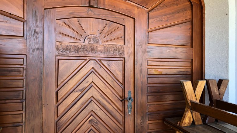 Denk wine tavern, © Donau Niederösterreich Wooden door with the inscription 'Weinbau Denk' and a sun above it.
