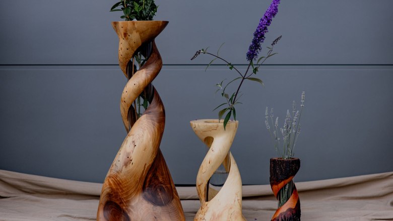 holzARTbinder - Works of art made of wood, © Waldviertel Tourismus, Matthias Streibel Three artfully turned wooden vases with flowers against a gray background.