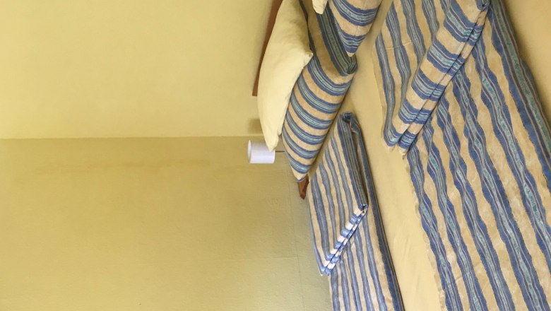 TDR House Maier bedroom, © Alicia Maier Bedroom with double bed, striped bed linen, yellow walls, small picture on the wall.