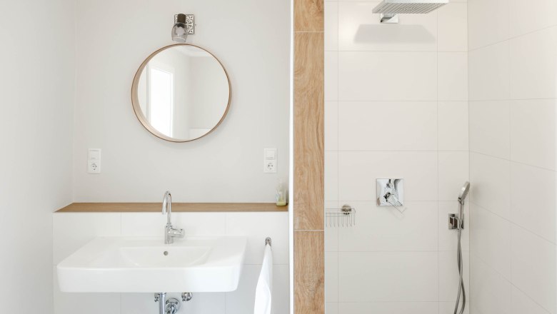 Bathroom Pinot Gris, © Michael Reidinger Modern bathroom with round mirror, washbasin and shower.