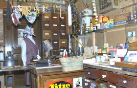 Kaufmann Museum Traiskirchen, © Museum Traiskirchen Interior view of a historic merchant's store with shelves full of old products and a mannequin in traditional clothing.