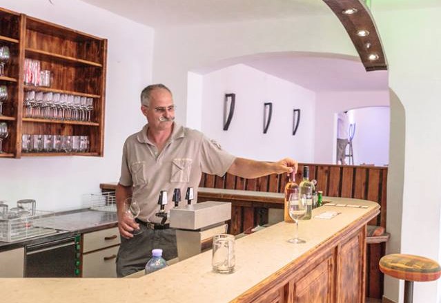 Winemaker Johann Frohner, © Weingut Frohner A man stands behind a wooden bar in a wine cellar and pours wine.