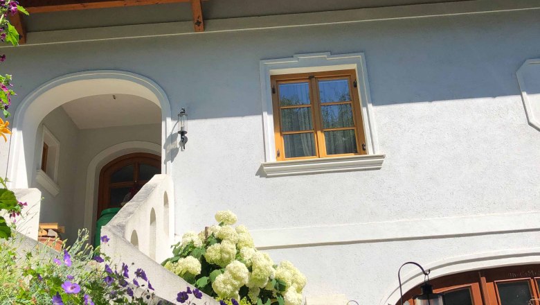 Viticulture Sandbichler, © Donau Niederösterreich House with white walls, wooden roof and flowers in the foreground.
