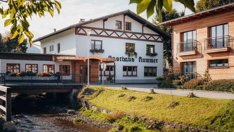 Inn in Gresten, © Niederösterreich Werbung/Daniela Führer A traditional inn with a white façade and wooden decorations next to a stream.
