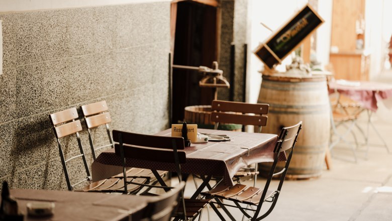 Refreshments in Bruck an der Leitha, © Niederösterreich Werbung/Michael Reidinger Cozy outdoor area of an inn with wooden tables and chairs.