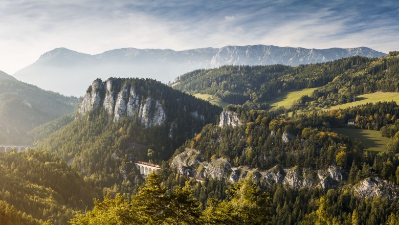 Semmering Railway, © NÖW Michael Liebert Panoramic view of the Semmering Railway in a mountainous landscape with forests and a viaduct.
