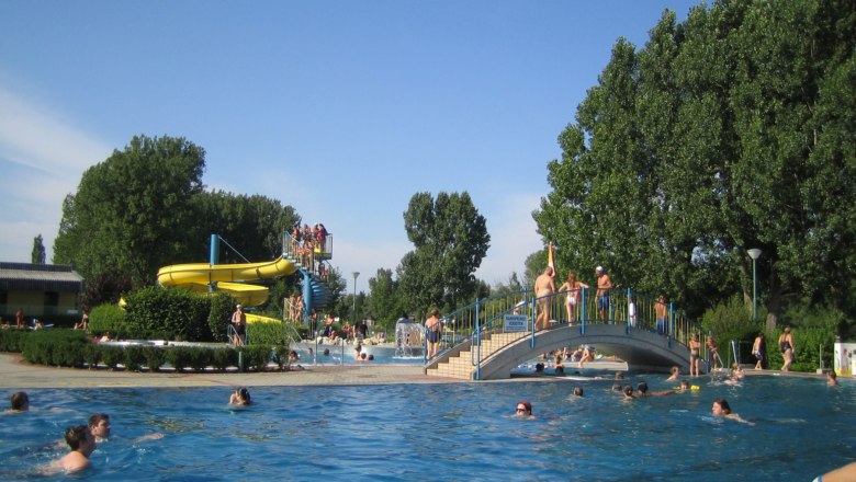 Our pools with water slide..., © strandbad Outdoor pool with water slide and bridge, lots of people in the water.