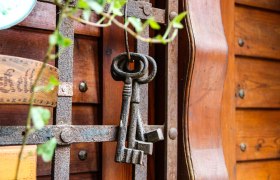Cellar key, © Mandler-Saul An old cellar key hangs on a rusty grille in front of a wooden wall.