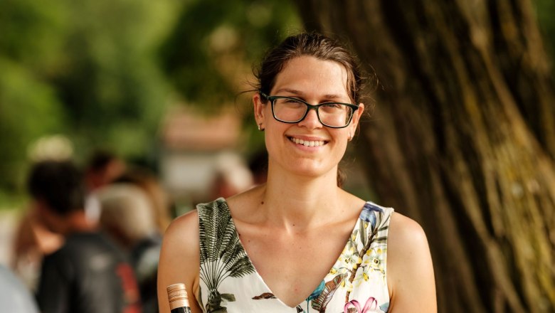 Agnes Lehner-Minkowitsch, © Michael Reidinger Woman with glasses holding a wine bottle outdoors.