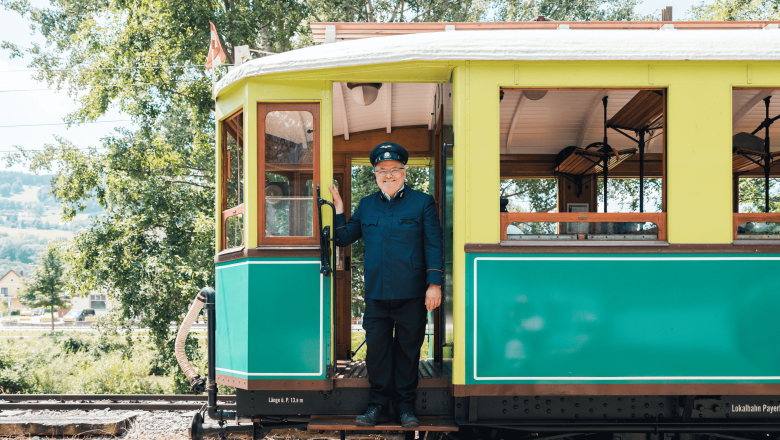Höllentalbahn, © Österreich Werbung/Stefan Strasser A train driver in uniform stands smiling in the doorway of a historic train.