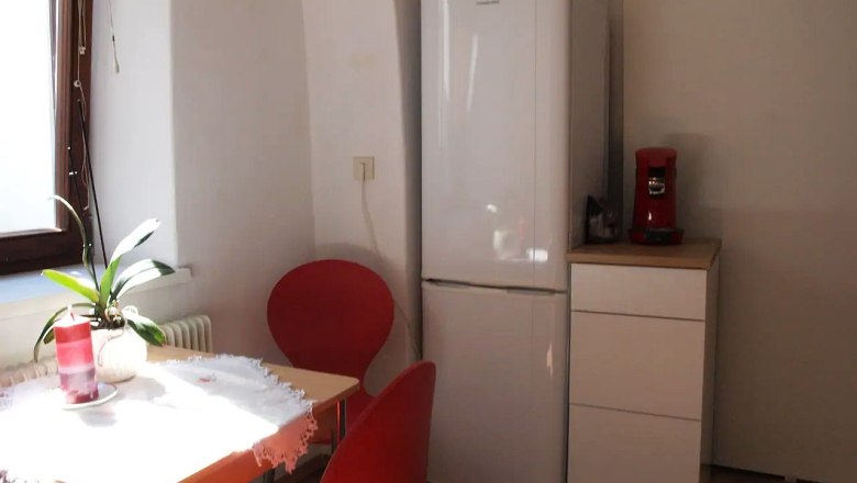 Dining area in the old town apartment Mathilde, © Fam. Obernberger Small kitchen with table, red chairs, fridge and coffee machine.