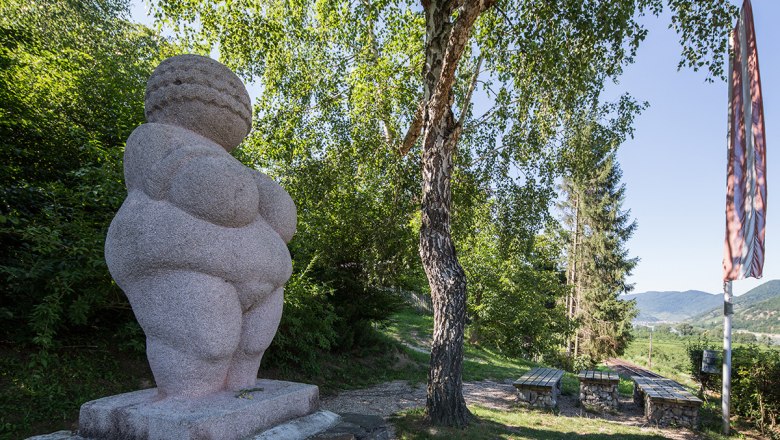 Venus of Willendorf, © Lachlan Blair Venus on a pedestal in the background tree and benches