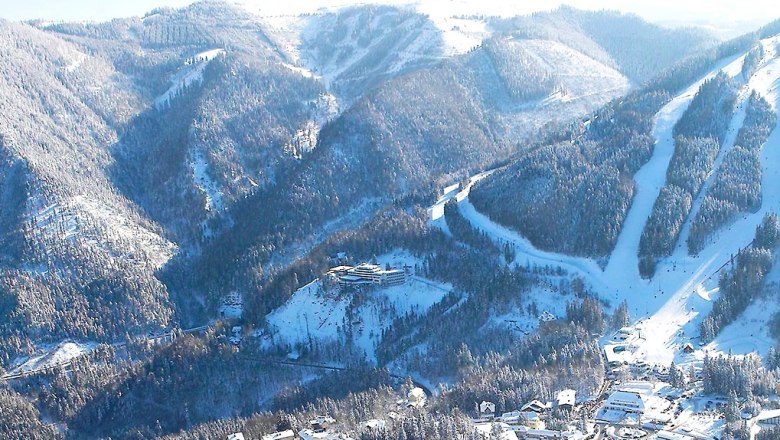 The Sporthotel Semmering in winter, © Sporthotel Semmering Aerial view of snow-covered mountains and a hotel in the Semmering region.