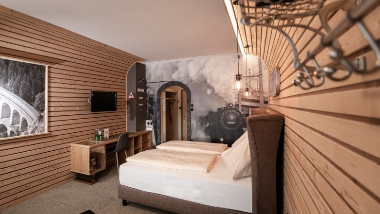 Gasthof Berghof, © Gasthof Berghof/Nici Seiser Hotel room with wooden walls, a double bed and a large mural of a steam locomotive.