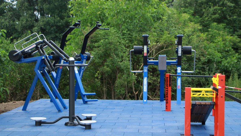 Motor skills park Ziersdorf, © R. Fischer Outdoor fitness equipment on blue outdoor floor tiles.