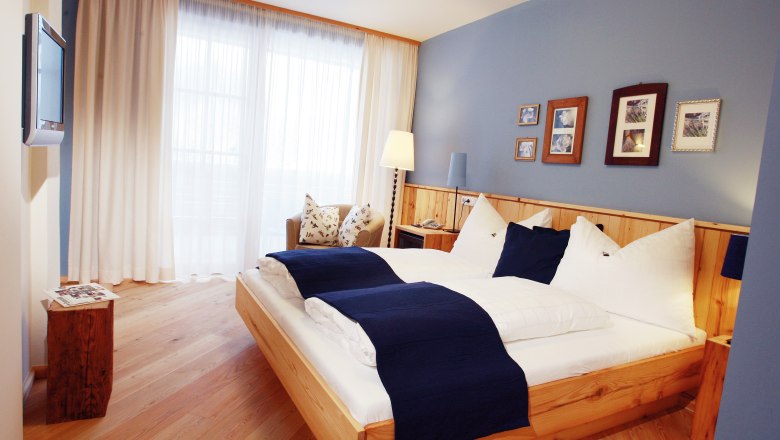 Hotel Fahrnberger, © Hotel Fahrnberger/weinfranz.at Cozy hotel room with double bed, blue accents and wooden furniture.
