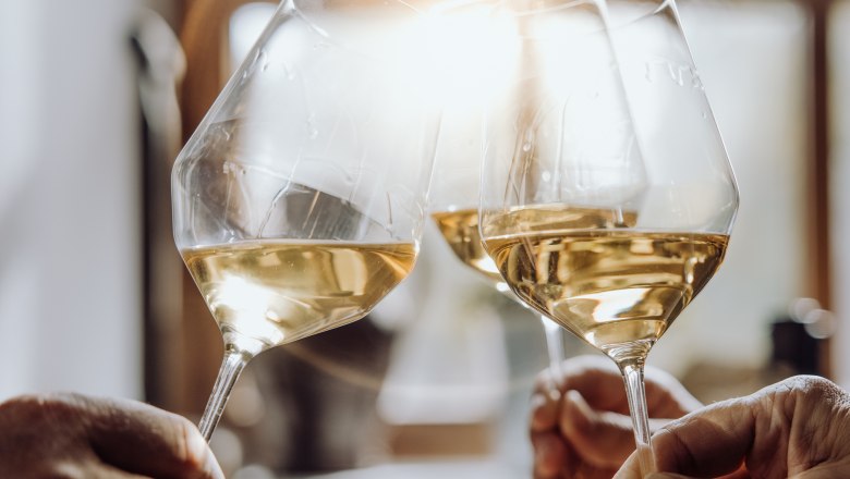 Toast the wine glass, © Weinviertel Tourismus GmbH / Creating Click Three people clink glasses of white wine, sunlight in the background.