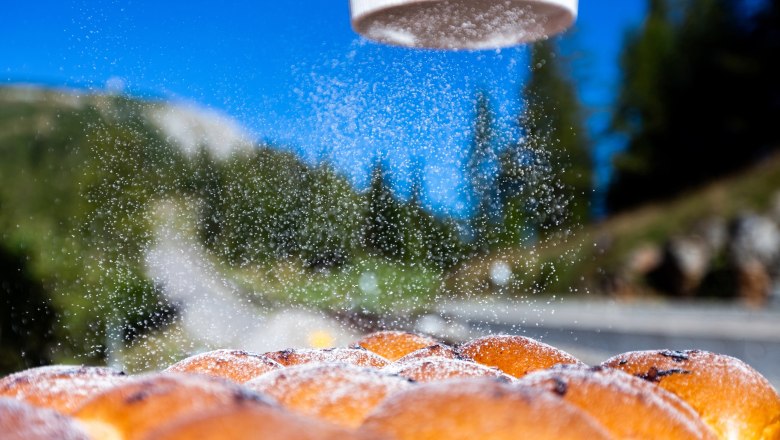 Baumgartnerhütte_Buchteln2(c)Christian Kremsl_G1B6299 (1), © Christian Kremsl Buchteln are sprinkled with powdered sugar, with a mountain landscape in the background.