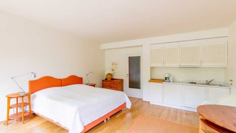 Bedroom, © Wiener Alpen / Christian Kremsl Bright bedroom with double bed, wooden furniture and small kitchenette.