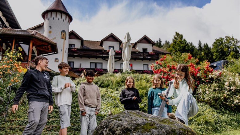 Fairytale Hotel Waldpension Nebelstein, © Waldviertel Tourismus, Matthias Streibel Children play with a sword in a stone in front of a hotel.