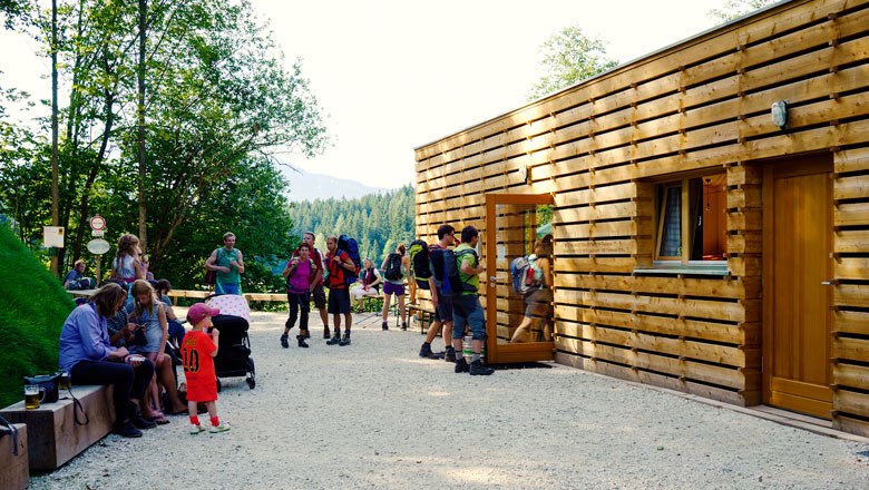 Stacking house entrance, © Harddecor Architektur People in front of a modern wooden building in a forest environment.