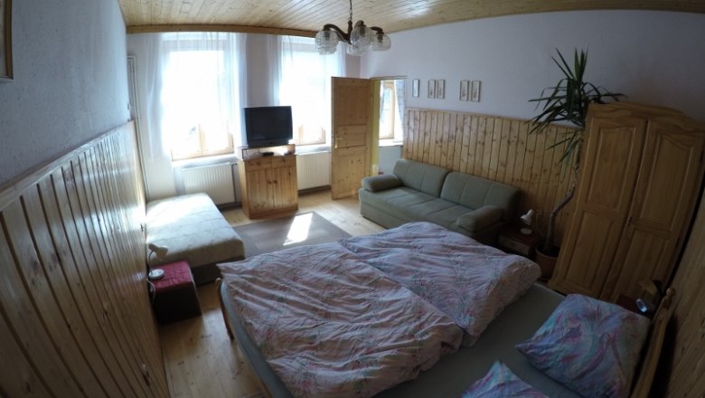 Bedroom vacation apartment 1, © dmgrauszer Cozy bedroom with double bed, sofa, TV and wooden furniture in a vacation apartment.
