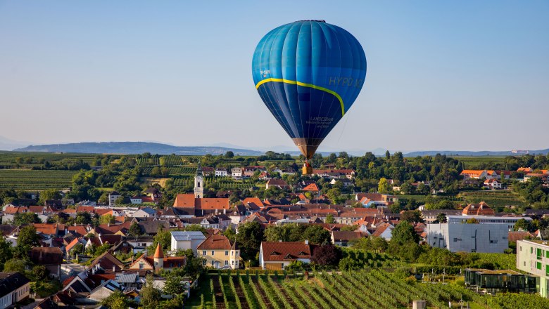 Balloon days Krems-Langenlois 2019 - Balloon flight over Langenlois, © Jürgen Übl Hot air balloon over a cityscape with vineyards and houses.