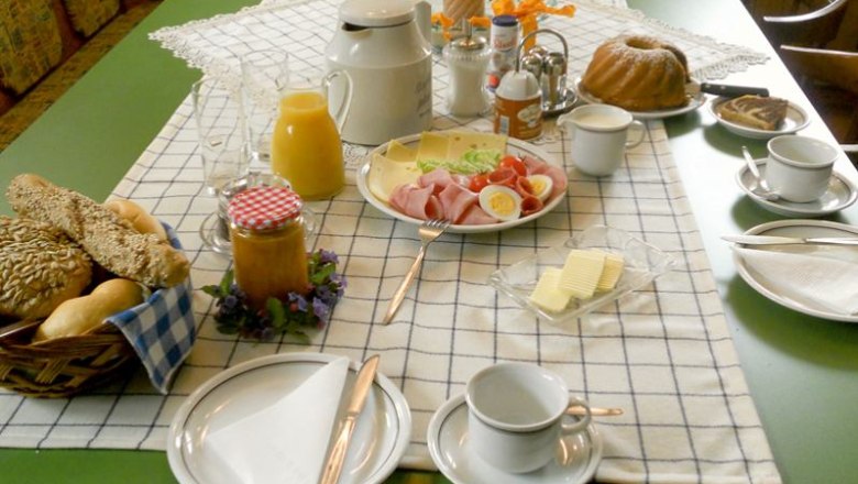 Breakfast, © Marschik A laid breakfast table with bread rolls, cold cuts, cheese, juice, coffee and cake.