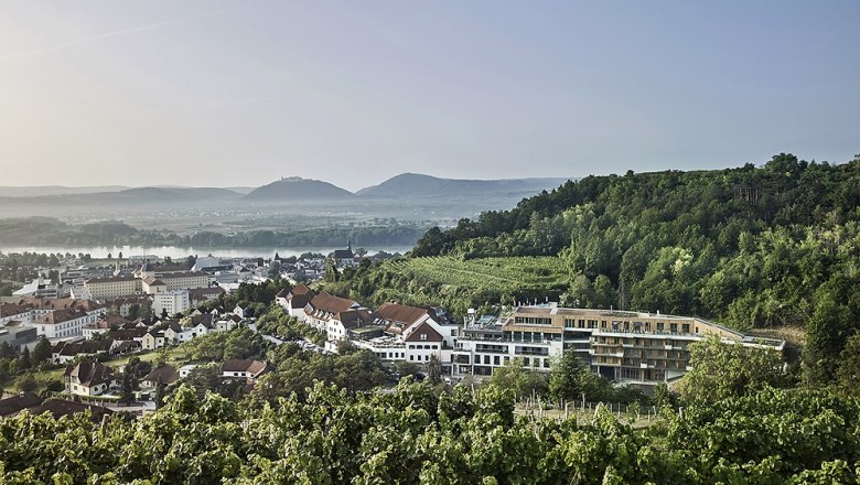 Steigenberger Hotel & Spa Krems, © Steigenberger Hotel & Spa, Gregor Titze View of the Steigenberger Hotel & Spa Krems surrounded by vineyards and hills.