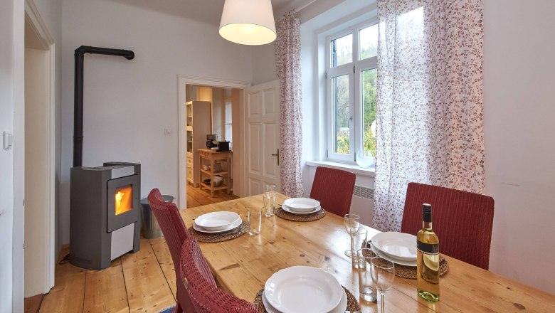 Top 1 - Dining room, © VP FeWo OG Dining room with wooden table, red chairs, set table and wood-burning stove.