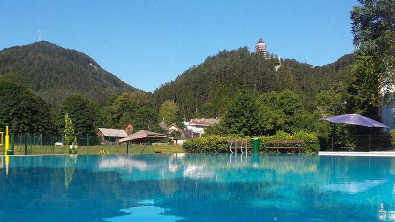 Outdoor pool Gutenstein, © Karl Denk Outdoor pool with a view of wooded hills and a tower in the distance.