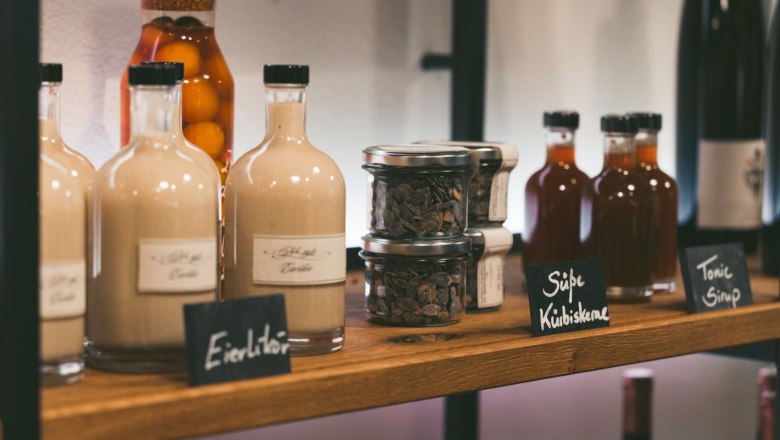 In-house greisslerei, © Hofmeisterei Hirtzberger/Julius Hirtzberger Shelf with bottles and glasses in a store.
