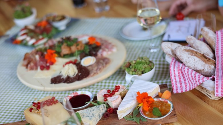 Delicious snack, © Manuela Winkler A laid table with cheese platter, bread, cold cuts and wine.